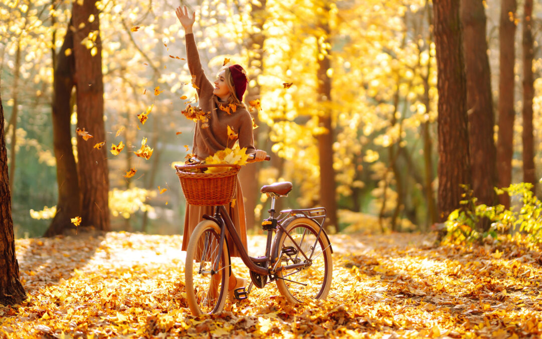 Frau wirft bunte Herbstblätter in die Luft
